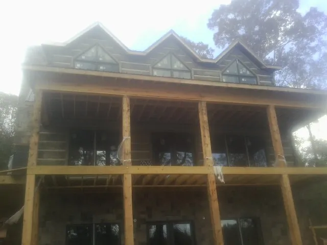 Dormers and porch framing on a large log home under construction — Roof Coating work by our crew in Gilsum
