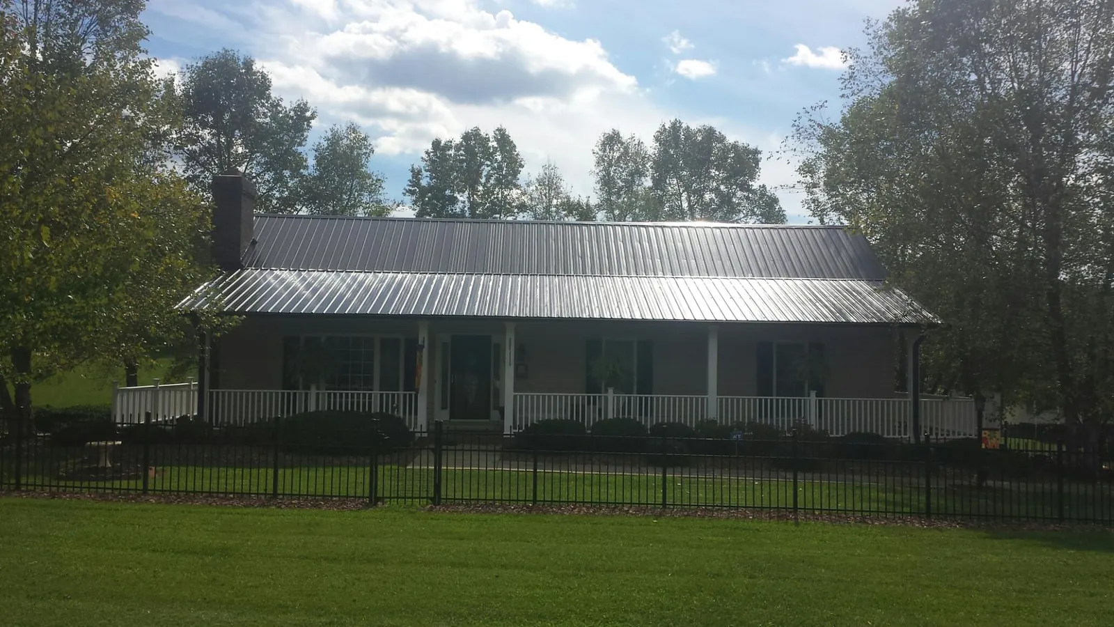 Gray metal roof on a brick ranch with a full width front porch — Gutter Guard Installation work by our crew in Gilsum