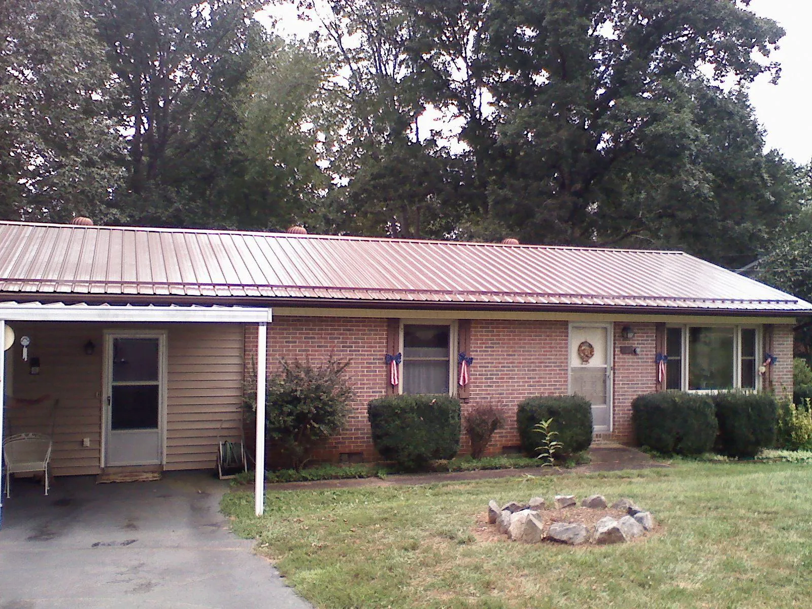 Bronze metal roof and carport on a brick ranch home — Roof Repair work by our crew in Gilsum