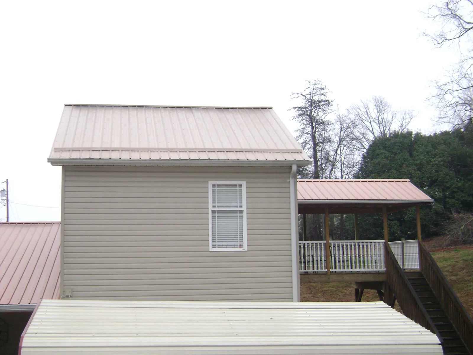 Tan metal roofs on a two story addition and attached porch, from a Roof Replacement job in Gilsum