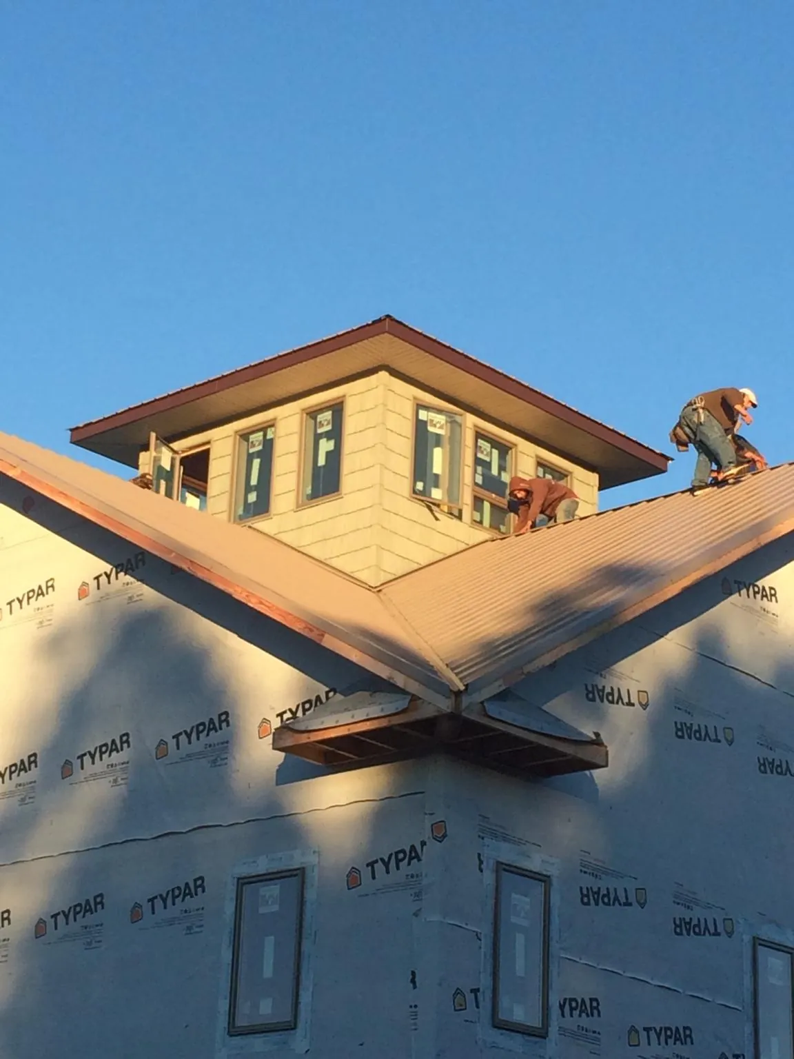 Roofers working around a rooftop cupola on a new metal roof at sunset — Roof Waterproofing in Gilsum by Roofing Brothers